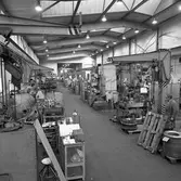 Arboga Mekaniska Verkstad, Meken, interiör. Två män arbetar i fabrikslokalen. Här ses maskiner, lastpallar och maskindelar.

25 september 1856 fick AB Arboga Mekaniska Verkstad rättigheter att anlägga järngjuteri och mekanisk verkstad. Verksamheten startade 1858. Meken var först i landet med att installera en elektrisk motor för drift av verktygsmaskiner vid en taktransmission (1887).  Gjuteriet lades ner 1967. Den mekaniska verkstaden lades ner på 1980-talet.
Läs om Meken i Hembygdsföreningen Arboga Minnes årsbok från 1982.