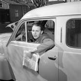 Arboga Tidning. Willy Johansson, anställd på tidningen, sitter bakom ratten med en bunt tidningar i handen.