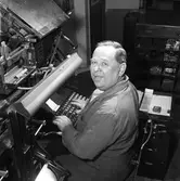 Arboga Tidning, personal och interiör.
En man, iklädd skyddsrock, arbetar med en maskin i tryckeriet.