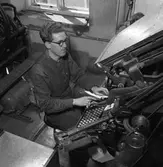 Arboga Tidning, personal och interiör. En man, iklädd skjorta och väst, arbetar med typer i tryckeriet.