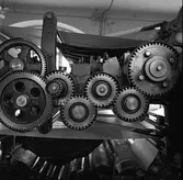 Arboga Tidning, interiör. Del av tryckpress. Kugghjul i närbild. Tidningspapperet löper upptill och nertill i bild.