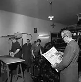 Arboga Tidning, personal och interiör. Några män i tryckeriet. Mannen närmast kameran, iklädd skyddsrock, håller i ett färskt exemplar av tidningen. En annan man håller i en tidningsbunt. Nils Munther ler mot fotografen.