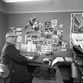 Arboga Tidning, personal och interiör. Sportjournalisten på sitt kontor. Mannen har en skrivmaskin med ett papper i. På väggen, framför skrivbordet, sitter sportfotografier och andra bilder.