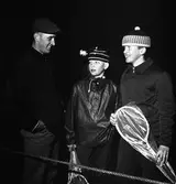 Arboganatta, orienteringstävling. En man och två pojkar, alla i ytterkläder. Pojkarna håller i var sitt badmintonracket. Det är så mörkt att inget annat syns i bilden.