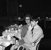 Arbogabor deltar vid radioprogrammet Frukostklubben, ett underhållningsprogram som sänds på lördagsmorgnar. En kvinna och en ung man sitter vid ett runt bord och dricker kaffe.