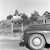 Motorhuven på en bil. Bilen färdas på en grusväg. En övervakningsspegel / 