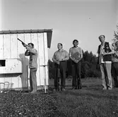 Lerduveskytte i Gyttorp. Skyttar från Arboga tränar.
Fem män syns på bilden. En skjuter. Två håller i sina gevär. En av dem har hörselskydd.