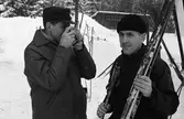 AT-loppet, skidtävling.
Mannen med kameran är Lennart Pettersson (Svarten). Han fotograferar Torsten Eriksson och hans skidor. Båda männen bor i Medåker.
(AT kan betyda Arboga Tidning)