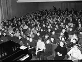 Barnfilmklubben. Nästan fullsatt i biosalongen. I förgrunden ses ett piano.