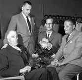 Brandkåren avtackar veteranerna Eric Jansson och Ture Arleij. Erik Jansson har varit brandmästare.
Mannen som står upp heter Ingvar Johansson och är ordförande i Brandstyrelsen. Mannen längst till höger är brandchef Gösta Jonsson.
I bakgrunden ses hyllan med alla brandhjälmar.