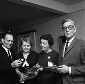 Einar Larsson i Hamre har fått en armbandsklocka. En kvinna håller i en blombukett.
Två män och två kvinnor. I bakgrunden anas en julgran.