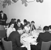 Elektrikerförbundets Arbogaavdelning firar jubileum. Uppklädda  män och kvinnor vid borden. Köttbullar och potatis på tallrikarna. Dekorationer på väggen.