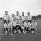 Kyrkofullmäktiges laguppställning. De ska möta stadsfullmäktige (se bild AKF-04200) i en fotbollsmatch.
Stående, från vänster: John Pettersson, Anna-Greta Åkersten, Bengt Samuelsson, Thure Berggren och Gösta Lindmark.
Sittande, från vänster: Charles Fernsten, Rolf Danielsson, Karl Pettersson, Thure Kühne och Rune Matsson.
Reinhold Carlssons text till denna bild:
Ett evenemang väl värt att infoga i Arbogas kommunalpolitiska historia såväl som i den mera sportbetonade. De båda fullmäktige, stads-och kyrko-, hade enats om ett möte för att avgöra vilka av de förtroendevalda som var de verkliga mästarna i lagsporten fotboll. tisdagen den 30 juni 1953 skulle det alltså avgöras. Sturevallen var matcharéna och till domare var Harald 