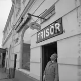 Frisörmästare Axel Fritiof Strandberg (kallad Atschy) vid sin salong på Stora torget, vägg i vägg med Nerikes Allehandas lokalkontor i Lundbergska huset.