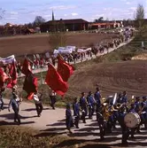 Första maj. Demonstrationståg på väg från stan till Folkets Park. Arboga Blåsorkester följs av fanbärare, Börje Sturk i mitten.
Byggnaden i bakgrunden är vårdcentralen. Strömsnäsbron är dekorerad med röda fanor.
Socialdemokrater