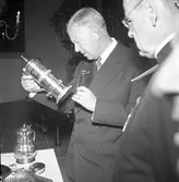 Konung Gustaf Vl Adolf gästar Arboga under sin Eriksgata. Här får han se den stora silversamlingen i Heliga Trefaldighetskyrkan. Till höger står prosten E Olof Björsell.
För värdskapet, under konungens besök, svarade stadsfullmäktiges ordförande Jonas Carlsson och kommunalborgmästare Danliel Ekelund. Den organisationskommitté som ansvarade för arrangemangen, hade hos drätselkammaren begärt en summa av 3000 kronor för att täcka kostnaderna vid kungabesöket. Beloppet beviljades. 
Tiden för kungens besök var beräknad till 130 minuter.