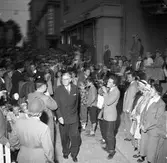 Konung Gustaf Vl Adolf gästar Arboga under sin Eriksgata. Här ses kungen i folkhavet på Stora torget med Rådhusgården till höger. Han har just passerat Hagmans Livs och Andelsslakteriet. Mannen till höger om kungen, med filmkameran, är Larz-Thure Ljungdahl.
För värdskapet svarade stadsfullmäktiges ordförande Jonas Carlsson och kommunalborgmästare Danliel Ekelund. Den organisationskommitté som ansvarade för arrangemangen, hade hos drätselkammaren begärt en summa av 3000 kronor för att täcka kostnaderna vid kungabesöket. Beloppet beviljades. 
Tiden för kungens besök var beräknad till 130 minuter.