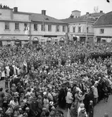 Publik på Stora torget. Kung Gustaf Vl Adolf besöker Arboga under sin Eriksgata. Mitt i bild ses Arboga Scoutkår.
I bakgrunden ses Lundborgska fastigheten med Konditori Saga och Järnaffären och människor på taket!
För värdskapet, vid konungens besök, svarade stadsfullmäktiges ordförande Jonas Carlsson och kommunalborgmästare Danliel Ekelund. Den organisationskommitté som ansvarade för arrangemangen, hade hos drätselkammaren begärt en summa av 3000 kronor för att täcka kostnaderna vid kungabesöket. Beloppet beviljades. 
Tiden för kungens besök var beräknad till 130 minuter.