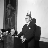 Hantverksföreningen delar ut mästarbrev. Platsen är fullmäktigesalen på Rådhuset. Mannen i talarstolen är okänd men närmast honom sitter Gustaf Johansson (kallad Murar-Gustaf).