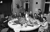 Lions damer julpysslar
Runt bordet, från vänster: Berit Munkberg, Siw Rudengård, Lilly Hedlund, Ella Högfeldt, Ingrid Hell-Carlsson (stående), Siri Wallström, Hill Eklöf, okänd, Ulla Björklund (stående), okänd, Gulli Lutteman och Märta Frising
På bordet ligger silkepapper, snören, julpapper, julgranskarameller, tomma hushållsrullar och bomullstussar. Mitt på bordet står två skäggiga tomtar.
Platsen kan vara Stadskällaren