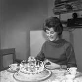 Britt-Marie Gustavsson har valts till årets Lucia. Här firar hon med kaffe och tårta hemma i köket. Bakom hennes rygg står kylskåpet och på en hylla står radion.