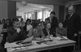 Lärare på kurs
Främre bänkraden, från vänster: Bo Lannsjö, Barbro Erjö, Karin Eriksson och Berit Torshage.
Stående, från vänster: Gunnar Bjurén och Bror Gustavsson (rektor).
På andra bänkraden sitter Birgitta Göransson.
På tredje bänkraden sitter Marianne Holmberg och längst bak, i salen, ses Inga-Britta Nanfeldt.
Böcker och papper ligger på bänkarna och en filmprojektor står i det bakre rummet.