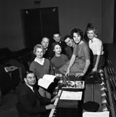 Revyrepetition. 
Bakre raden, stående från vänster: Anders Wadström (aktör och författare), Arne Johnsson (batterist) och Larz-Thure Ljungdahl (aktör och författare)
Främre raden, stående från vänster: Lisbeth Söderström-Alsbro (aktör) och Ulla-Britt Andreasson (aktör)
Sittande, från vänster: Gösta Kling (kapellmästare), Eva-Britt Lindvall (aktör) och Gunilla Lindström (aktör)
Revyn hette 
