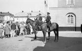 Riksdagen 550 år. Jubileet firas i Arboga. Två ridande poliser på Rådhusgatan.
Publiken trängs bakom avspärrningen på Stora torget.