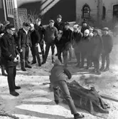 Skolelever övar brandsläckning. Brandman Håkan Waern instruerar. Det är snö och kallt. Många av pojkarna har mössa på sig.
De håller till bakom brandstationen på Strandvägen.