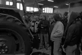 En skolklass är på studiebesök på Närkes Maskiner. En traktor i blickfånget. Läraren Sixten Öhman, längst till vänster. Bredvid honom, i randig sjal, står Thomas Öhling.