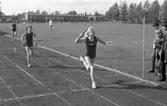 Skolmästerskap på Sturevallen. Stafett för flickor. Vinnande lagets sista löpare, Agneta Persson (gift Bode) på väg mot målsnöret.
Vid målstolpen står tre personer och tittar på. Den vänstra av den heter Jinnerstrand.