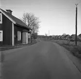 Skräddare Sundells hus, vid Hamrevägen, ska rivas.
Tvåvånings trähus med förstugan nästan på vägen.
Telefonstolpe.
Nybyggda villor till vänster.