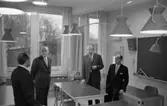 Invigning av Stureskolan. Fyra kostymklädda herrar bland skolbänkar och stolar i ett klassrum. Mannen med ryggen mot fotografen är troligen Tore W Ekman. Bredvid honom står rektor Bror Gustavsson. De andra två är okända.