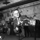 Tapetserare Fritz Lindkvist i sin verkstad i en del av Fahlströmska gården vid Ahllöfsgatan. Han arbetar med en tygklädd pall. På väggen, bakom honom, ses en klocka och en telefon. På en hylla står en portfölj.
Lindkvist etablerade sig här 1907.
Lindqvist