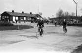 Män som cyklar hem från arbetet på CVA, Centrala Verkstaden Arboga. I bakgrunden ses grinden och 