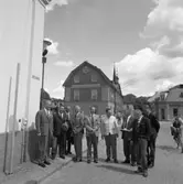 Turisttrafiknämnden på besök. Nils Brodin och Nils Forsberg är värdar. En kvinna på cykel. 
Gruppen står i hörnet Stora torget - Västerlånggatan, intill Lundborgska fastigheten. Bakom dem anas Rådhusets innegård, Rådhuset och Svenska Handelsbanken i Kungsgården.