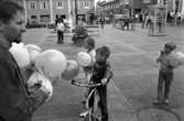 Socialdemokraterna har valmöte på Nytorget. Per-Olov Nilsson delar ut ballonger. På torget ses fontänen och en telefonkiosk. Människor rör sig över torget. Barn med cyklar. Bilar åker på Nygatan.