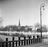 Vintermotiv från Herrgårdsbron. Utsikt över fastigheter på Strandvägen. Mitt i bild ses Heliga Trefaldighetskyrkan. Till vänster om den ligger Brandstationen.
Det är vinter och snö. Broräcke och lyktstolpe.