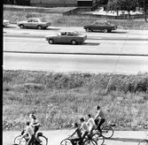 Cyklister och bilförare på Västermovägen, Brattberget. Daghemmet Biet ses i bakgrunden.