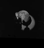 Lokalrevyn 1959
En ensam kvinna på scenen, en jordglob i bakgrunden.