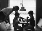 Arboga Stadsbibliotek, interiör. Bibliotekarie Lotta von Plomgren ser på när två pojkar spelar schack.
