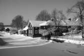 Utsikt från Kapellbron. Ågårdar i vinterskrud. Is och snö på Arbogaån.
Fastigheterna ligger längs Västerlånggatan.