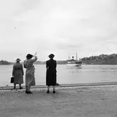 Tre kvinnor vinkar av en båt från Skeppsbrokajen i Stockholm.