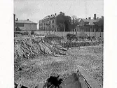 Fastigheten kv Trädgården 6, Varberg. Grundschaktning för Domusbygget är klart. Artikel i samband med bilden publicerad i Varbergs Tidning 1962-05-07.
Fotot visar den urschaktade marken och omgivningarna. Fastigheterna i bakgrunden är Läkaren 9, (Varbergs stadshotell), Rappeska huset (revs 1969?) och en del av Brunnsparken 5.