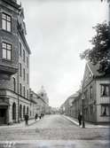 Skolgatan mot väster från Kyrkogatan i Jönköping. Till vänster, Kyrkogatan 12, ett av de äldsta tegelhusen i staden, ritat av stadsarkitekt Fredrik Sundbärg år 1897. Till höger ses Ljungs Platsanskaffningsbyrå.