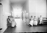 Sjukvårdspersonal och patienter i en korridor, Östhammars lasarett, Uppland
