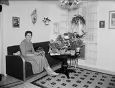 Kvinna i bostadsmiljö med blommor på ett bord, Östhammar, Uppland
