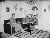 Kvinna i bostadsmiljö med blommor på ett bord, Östhammar, Uppland