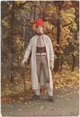 Vykort med motiv från Skansen. Enkel helgdagsdräkt, Delsbo socken, Hälsingland.