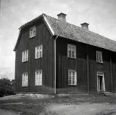 Mangårdsbyggnaden med träpanel och mansardtak, i Rumma.